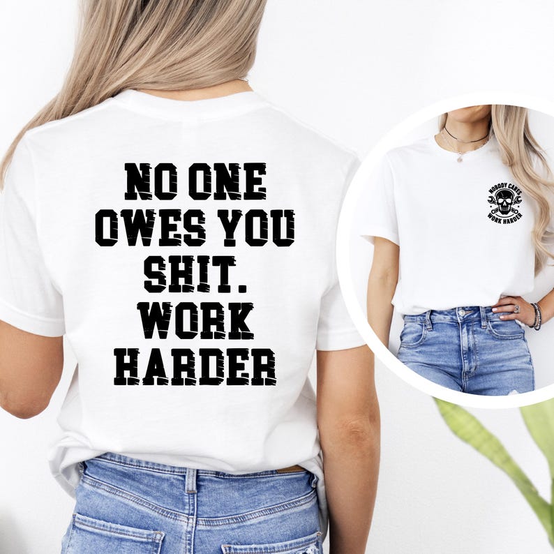 May include: White t-shirt with the text "NO ONE OWES YOU SHIT. WORK HARDER" in bold black letters on the back. A smaller image of a skull with tools is on the front. The shirt is paired with blue jeans.