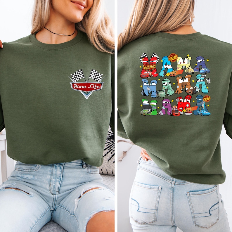 May include: An olive green sweatshirt featuring a "Mom Life" graphic with checkered flags on the front. The back displays a colourful graphic of cartoon cars arranged to form letters.