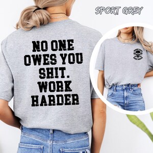 May include: Sport grey t-shirt with the text "NO ONE OWES YOU SHIT. WORK HARDER" in black block letters on the back. The front of the shirt has a small skull graphic with the words "NOBODY CARES WORK HARDER".