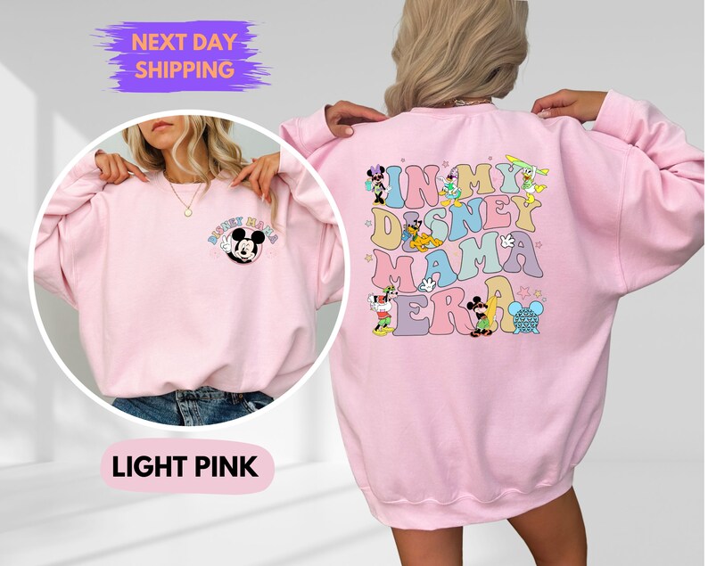 May include: Light pink sweatshirt with a Mickey Mouse graphic on the front and "In My Disney Mama Era" text with Disney characters on the back.