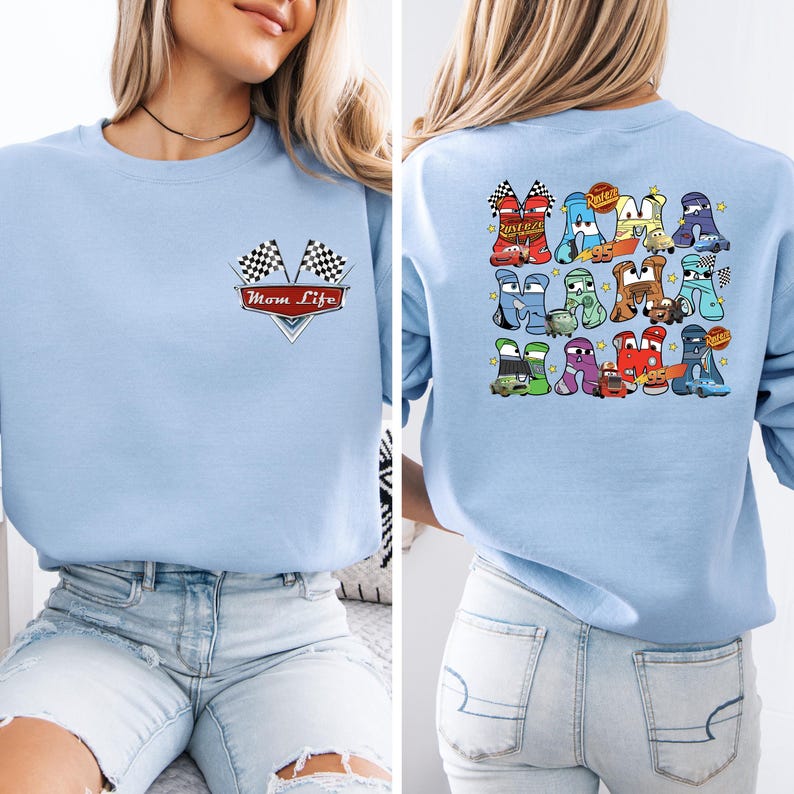 May include: Pale blue sweatshirt with a Mom Life graphic on the front, featuring checkered flags and a red banner. The back displays a colourful car-themed design with the word "Race" and various car illustrations.