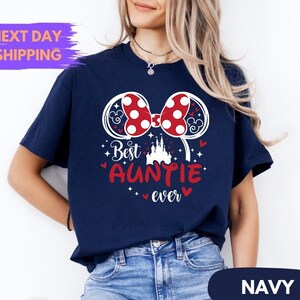 Puede incluir: Camiseta azul marino con un dise&ntilde;o de lazo de lunares rojos y blancos y las palabras "Best Auntie Ever" en rojo. La camiseta tambi&eacute;n presenta un gr&aacute;fico de castillo y la palabra "Navy" en la parte inferior.
