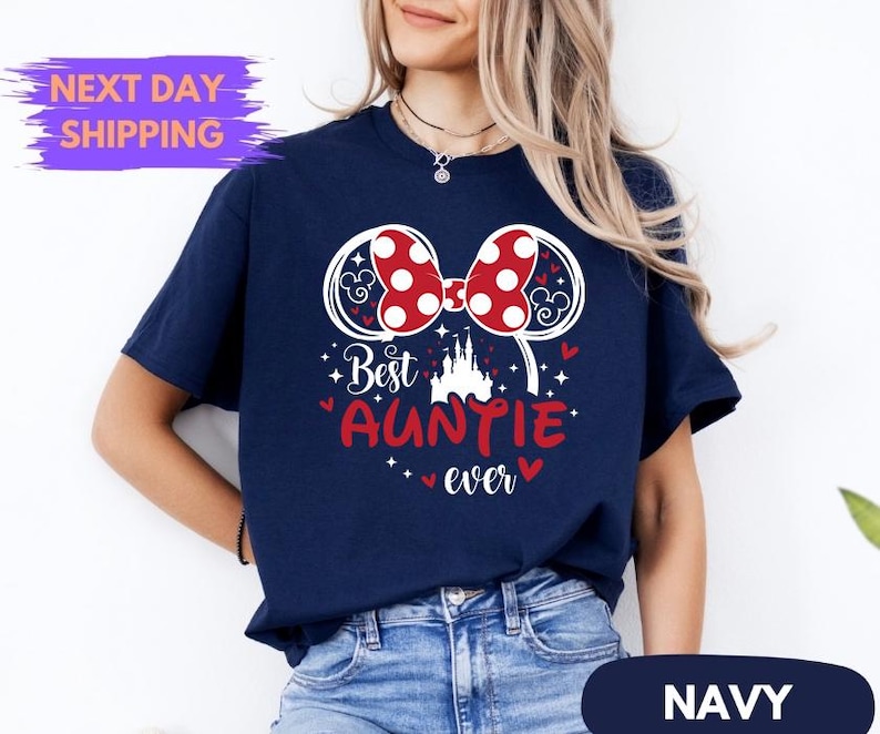 Puede incluir: Camiseta azul marino con un dise&ntilde;o de lazo de lunares rojos y blancos y las palabras "Best Auntie Ever" en rojo. La camiseta tambi&eacute;n presenta un gr&aacute;fico de castillo y la palabra "Navy" en la parte inferior.