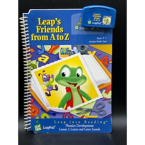以下が含まれることがあります： Leap's Friends from A to ZというタイトルのLeapFrog LeapPadスパイラル綴じブックと、その上に置かれた青いゲームカートリッジ。表紙には緑色のカエル、紫色の昆虫、学用品、文字が描かれています。対象年齢は4歳から7歳までです。
