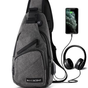 May include: A grey sling backpack with a single shoulder strap, featuring multiple zippered compartments, a black buckle, and the brand name INNOSCENT printed on the front. A smartphone and black over-ear headphones are connected via cables.