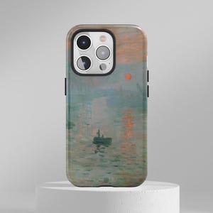 May include: A mobile phone case displaying a painting of a sunrise over water. The artwork uses orange, blue, and green colours. The case has a black frame and a camera cutout.