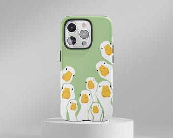 May include: A green phone case featuring a pattern of cartoon white ducks with yellow beaks. The ducks are arranged in a playful, overlapping design. The phone case has a black camera border.