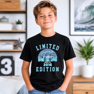 Könnte beinhalten: Ein schwarzes T-Shirt mit kurzen Ärmeln und einem Grafikdesign mit dem Schriftzug "LIMITED EDITION" in Hellblau. In der Mitte befindet sich eine blaue Sonnenuntergangsgrafik mit dem Namen "Fabian" und dem Text "BORN IN 2016" in Weiß und Blau.