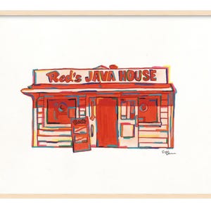 May include: A framed art print of "Red's JAVA HOUSE" in a vibrant, colorful style. The artwork depicts a small, red building with a sign, door, and windows. A small sign reads "BACK". The artwork is framed in a light wood frame.