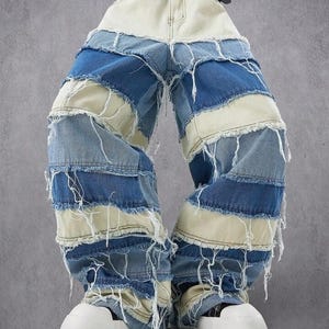 Puede incluir: Vaqueros patchwork en tonos azules y crema con bordes deshilachados. Los vaqueros tienen una cintura alta y se aseguran con un cinturón negro con hebilla plateada. Zapatos de plataforma blancos completan el look.