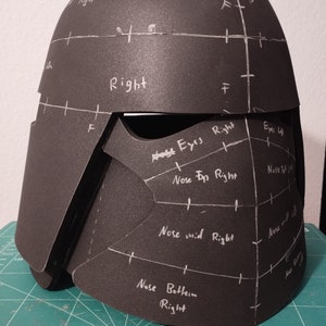 Könnte beinhalten: Ein schwarzer Schaumstoffhelm mit weißen Markierungen und handschriftlichen Notizen, darunter "Eyes Right", "Nose Top Right" und "Nose Bottom Right".
