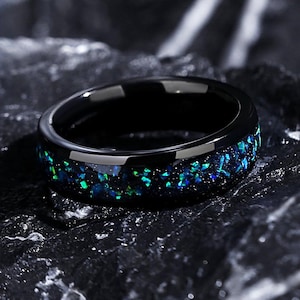 May include: A black ring with a band of blue and green opal glitter.