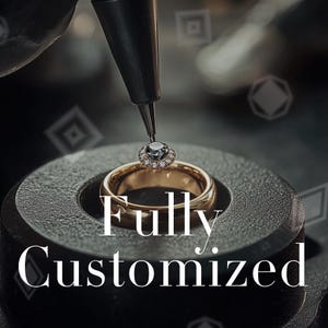 Op de afbeelding: Een close-up van een gouden ring met een diamant halo zetting die met een gereedschap wordt bewerkt. De ring ligt op een donkergrijze ondergrond. De tekst "Fully Customized" wordt in het wit weergegeven.