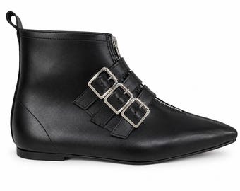 May include: Black leather ankle boots with a pointed toe and a zipper closure. The boots feature three silver buckles across the top and a small loop at the back. The design is sleek and modern, suitable for various outfits.