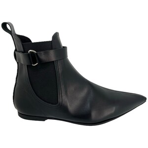 May include: Black leather ankle boots with a pointed toe and a buckle strap. The boots have an elastic side panel and a flat heel.