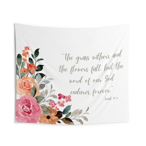 Puede incluir: Un tapiz blanco con un diseño floral en la esquina inferior izquierda. El tapiz presenta una cita de la Biblia: "La hierba se seca y la flor se marchita, pero la palabra de nuestro Dios permanece para siempre." Isaías 40:8