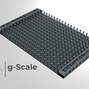 Puede incluir: Un accesorio de modelismo de plástico gris a escala 1/12 con una cuadrícula de pequeños tornillos y arandelas. El accesorio está etiquetado como "1/12 Mini Bolt Heads & Washers".