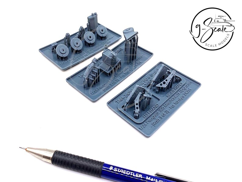 Op de afbeelding: Drie grijze plastic model auto onderdelen voor een Peugeot 205 op schaal 1:24. De onderdelen zijn gelabeld met "Linkerhand", "Rechterhand" en "TAM 24/6".