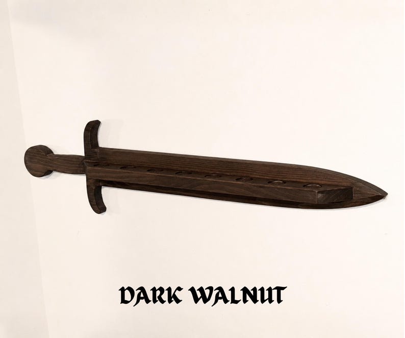 May include: A dark walnut wall-mounted display rack shaped like a sword. The wooden sword features a horizontal blade with a series of circular cutouts along the top edge for holding items. The text "DARK WALNUT" is printed below the object.