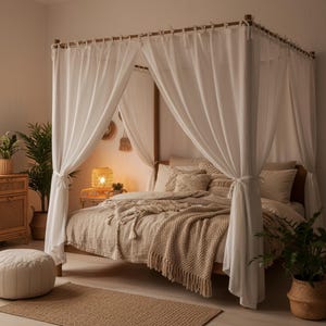 Puede incluir: Una cama con dosel de madera con cortinas blancas. La cama está hecha con una colcha beige y cojines. Una alfombra tejida y una mesita de noche con una lámpara están en primer plano. Las plantas en macetas añaden un toque de vegetación al dormitorio.