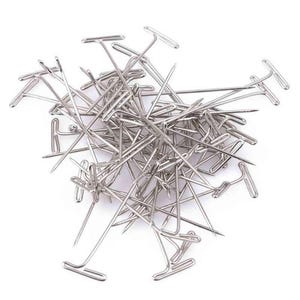 May include: A pile of silver T-pins, also known as dressmaker pins, used for holding fabric together while sewing.