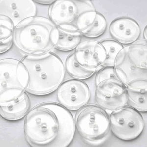 May include: A collection of clear plastic buttons of various sizes. The buttons have two holes each.