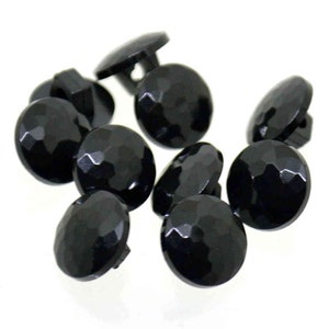 May include: A group of ten black plastic buttons with a faceted design. The buttons have a shank for sewing.