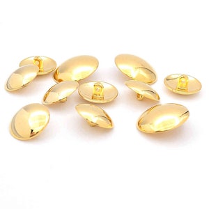 May include: Ten gold-coloured, round, flat-backed buttons with a single hole in the centre.