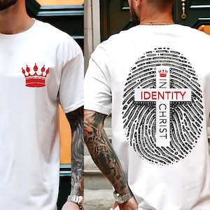 May include: White t-shirt with a red crown on the front and a black and white fingerprint design with a cross and the text "IN CHRIST IDENTITY" on the back.