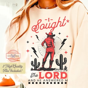 May include: Cream-colored sweatshirt with a graphic of a cowgirl in red attire, cacti, and lightning bolts. The text reads "I Sought The LORD and He Answered Me" with "Psalm 34:4" below. Includes a small logo that says "Original Designer".