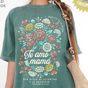 May include: Green t-shirt with a floral design in red, yellow, and white. The words "Te amo mamá" are featured prominently, with additional text in Spanish. The shirt includes the text "DOS ARCHIVOS DE ALTA CALIDAD INCLUIDOS" and "DISENADORA 4EVER SAVED ORIGINAL".