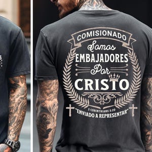 Peut inclure: T-shirt gris foncé avec texte blanc. Le devant affiche "EMBAJADORES Por CRISTO" avec une couronne. Le dos présente un motif plus grand avec "COMISIONADO Somos EMBAJADORES Por CRISTO" et "2 CORINTHIANS 5:20 ENVIADO A REPRESENTAR".