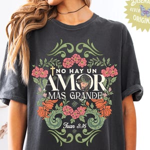 May include: A black t-shirt with a floral design and the text "No hay un amor mas grande" with a cross and a depiction of Jesus. The text "Juan 3:16" is also included.