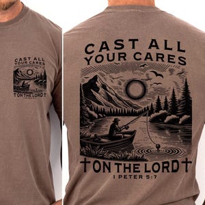 Puede incluir: Camiseta marrón de manga larga con un gráfico en la parte delantera y trasera. El gráfico frontal muestra un barco en un lago con el texto "CAST ALL YOUR CARES ON THE LORD". El gráfico trasero muestra un pescador en un bote con el texto "CAST ALL YOUR CARES ON THE LORD I PETER 5:7".