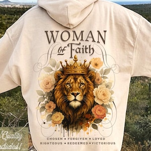 Puede incluir: Sudadera con capucha color crema con un león coronado, rodeado de rosas. El texto "WOMAN of Faith" está encima del león, con texto adicional debajo. La sudadera tiene el texto "4 High Quality Files Included!" y "Original Designer 4EVER SAVED".