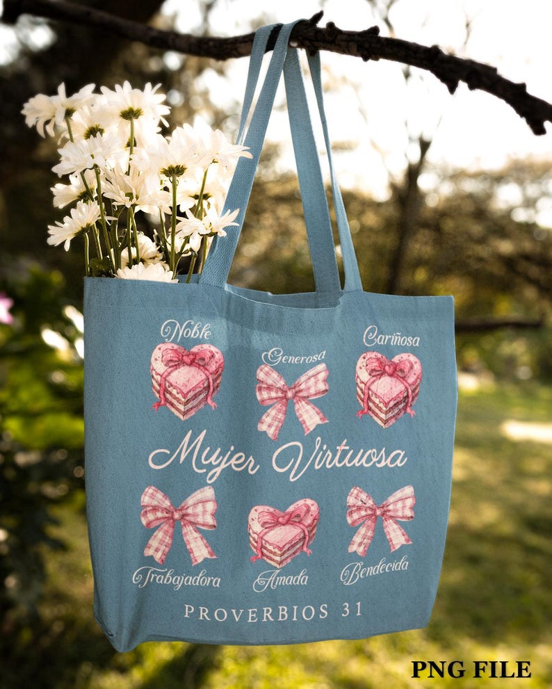 May include: A light blue tote bag with a pink and white design. The bag features the text "Mujer Virtuosa" and "Proverbios 31" along with illustrations of hearts and bows. The text "Noble, Generosa, Cari&ntilde;osa, Trabajadora, Amada, Bendicida" is also included.