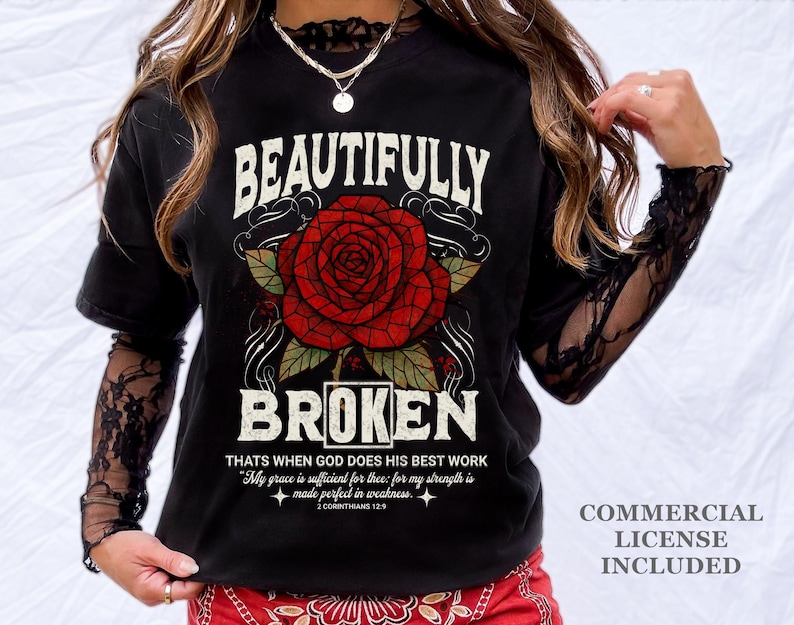 May include: Black t-shirt with a large red rose graphic and the words "BEAUTIFULLY BROKEN". The shirt also features a quote from 2 Corinthians 12:9. The shirt has long sleeves with a lace design.