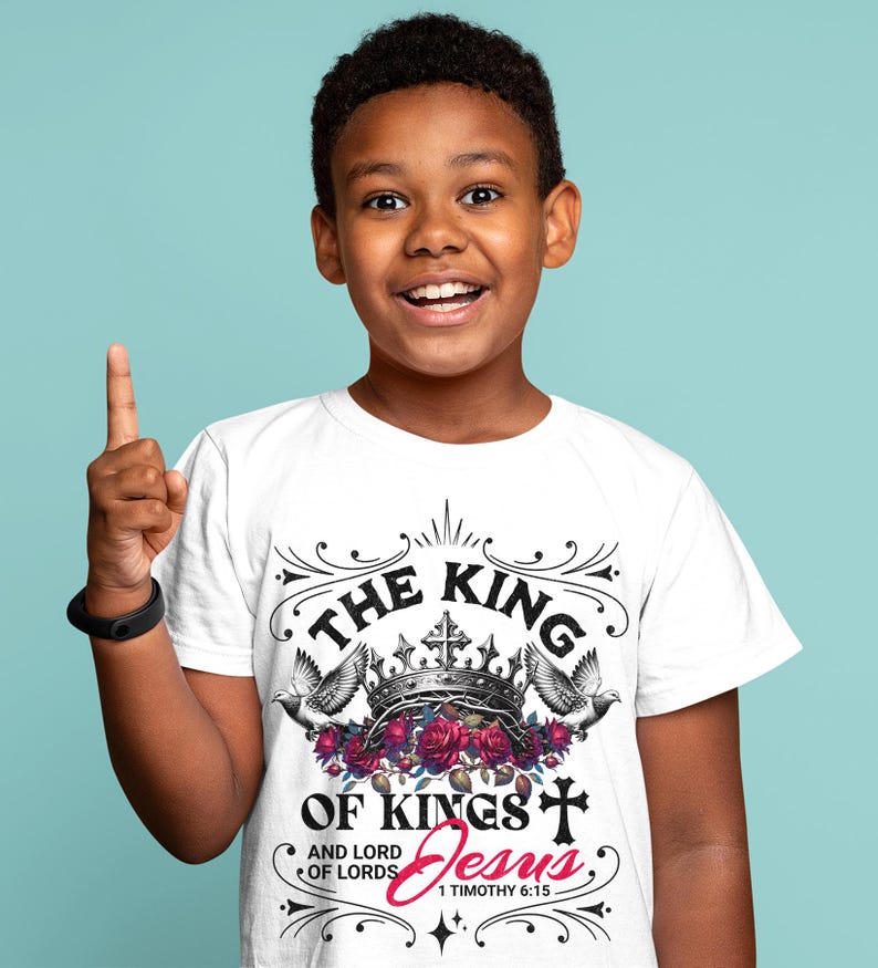 May include: White t-shirt with a black graphic design that says "The King of Kings and Lord of Lords Jesus 1 Timothy 6:15". The graphic features a crown, doves, and roses.