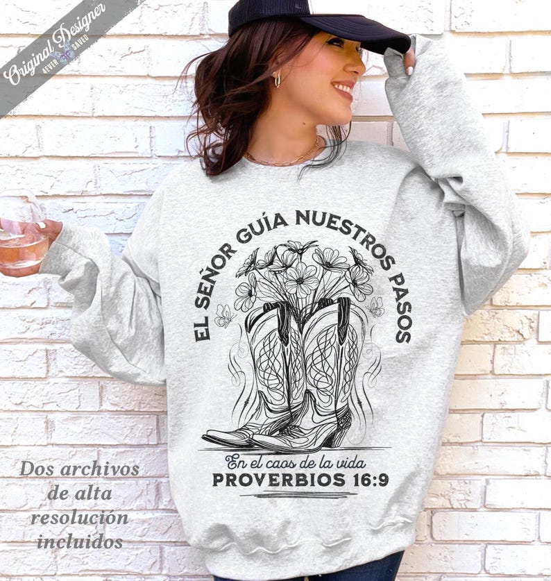 May include: A light gray sweatshirt with a graphic of cowboy boots filled with flowers. The text "EL SE&Ntilde;OR GU&Iacute;A NUESTROS PASOS" and "PROVERBIOS 16:9" are printed on the sweatshirt. The words "Original Designer" are also printed on the sweatshirt.