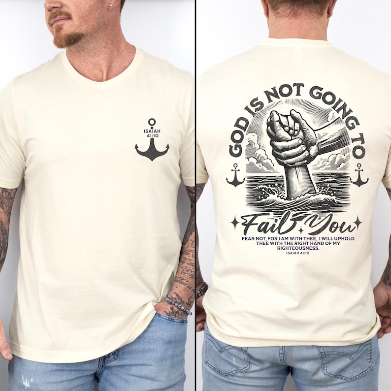 Op de afbeelding: Een cr&egrave;mekleurig T-shirt met een zwarte ankergrafiek op de linkerborst en een zwarte grafiek op de rug die zegt "God zal je niet in de steek laten" met een zwart-witte illustratie van een hand die naar beneden reikt om iemand in het water te helpen. De tekst bevat ook de Bijbeltekst Jesaja 41:10.
