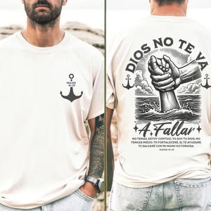 May include: Cream-colored t-shirt with a black anchor graphic and the text "ISAIAS 41:10" on the front. The back features a graphic of a hand emerging from water, with text in Spanish: "DIOS NO TE VA A Fallar" and "ISAIAS 41:10".