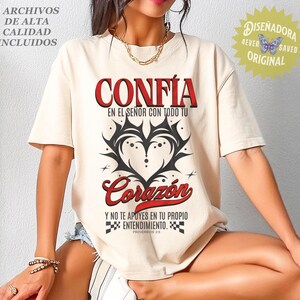 May include: Cream-colored t-shirt with the Spanish words "CONF&Iacute;A" and "Coraz&oacute;n" in red, along with black graphic heart design. The shirt also features text in Spanish and the phrase "4 ARCHIVOS DE ALTA CALIDAD INCLUIDOS".
