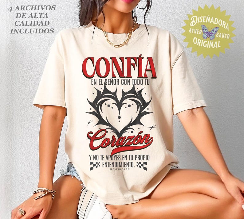 May include: Cream-colored t-shirt with the Spanish words "CONF&Iacute;A" and "Coraz&oacute;n" in red, along with black graphic heart design. The shirt also features text in Spanish and the phrase "4 ARCHIVOS DE ALTA CALIDAD INCLUIDOS".