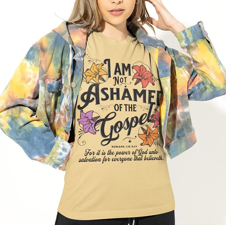 May include: A tan t-shirt with a floral design and the text "I AM NOT ASHAMED OF THE GOSPEL" with the Bible verse "ROMANS 1:16 KJV" and the text "For it is the power of God unto salvation for everyone that believeth."