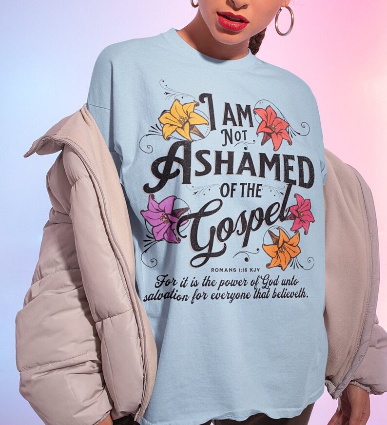 May include: Light blue t-shirt with a floral design and the text "I am not ashamed of the Gospel" with a Bible verse reference.