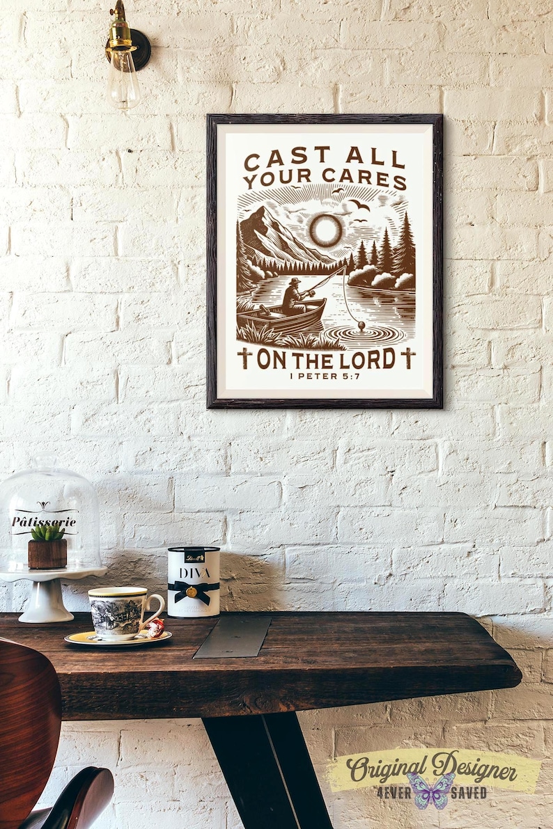 May include: A framed print with the text "CAST ALL YOUR CARES ON THE LORD I PETER 5:7" features a brown and white illustration of a person fishing on a lake with mountains in the background. The print is displayed on a white brick wall.