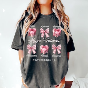 May include: A gray t-shirt with a pink and white design featuring a heart with a bow and the text "Mujer Virtuosa" and "PROVERBIOS 31".
