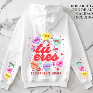May include: White hoodie with a colorful graphic on the back that says "t&uacute; eres" with hearts that say "amada", "fuerte", "elegida", "libre", "salvada", and "perdonada". The sleeves have hearts that say "amada", "libre", and "fuerte".
