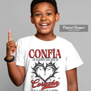 May include: White t-shirt with the Spanish words "CONFIA" and "Coraz&oacute;n" in red and a black heart design. The shirt also includes the text "EN EL SE&Ntilde;OR CON TODO TU" and "Y NO TE APOYES EN TU PROPIO ENTENDIMIENTO."