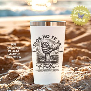 May include: A white travel tumbler with a silver rim, featuring a black and white illustration of a hand emerging from water, with the words "DIOS NO TE VA A Fallar" and other text. The tumbler is on a sandy beach.